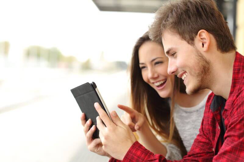Happy couple watching videos or sharing media content from a tablet